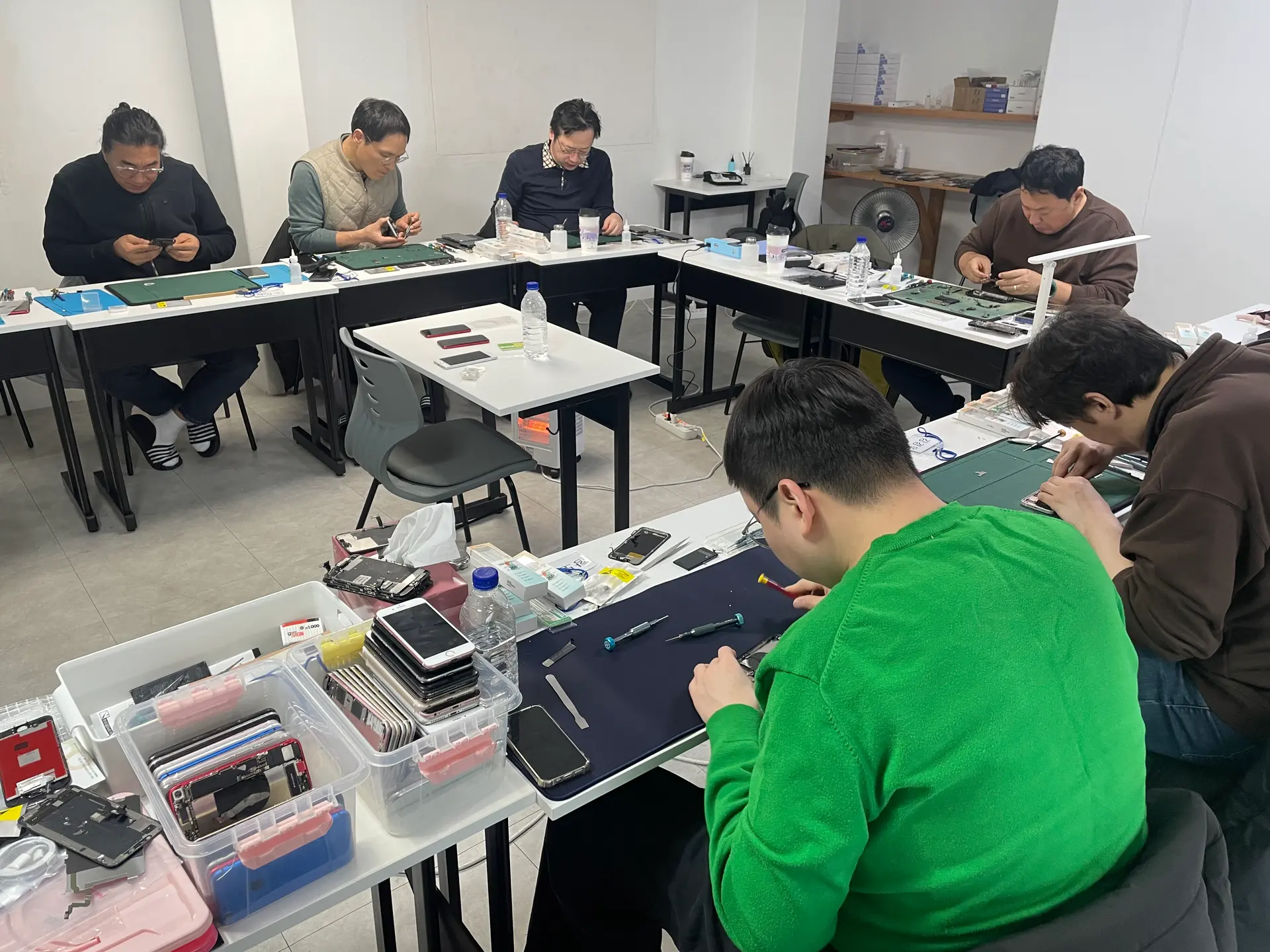폰수리 교육 현장에서 수강생들이 실제 스마트폰을 분해하며 수리 기술을 실습하고 있는 모습