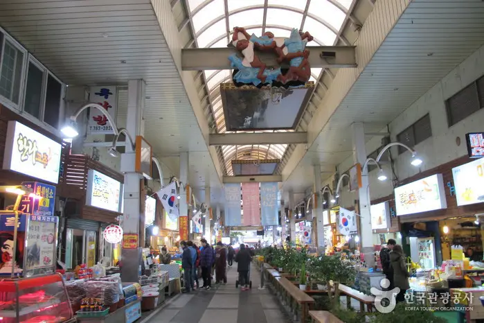Indoor view of Seogwipo Maeil Olle Market in Jeju Island, South Korea, with local vendors, food stalls, and Korean flags — a cultural hotspot for Muslim-friendly family travel.