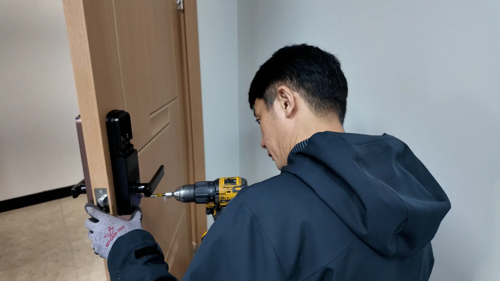 문에 전동드릴로 도어락을 설치하는 기술자 모습