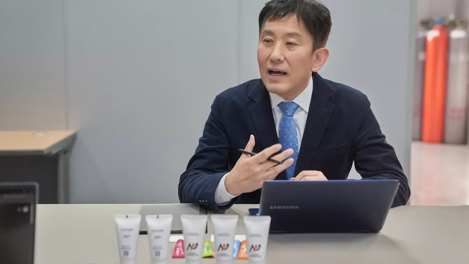 미소팜에서 제조한 치약과 노트북을 앞에 두고 설명하는 정장 차림의 남성