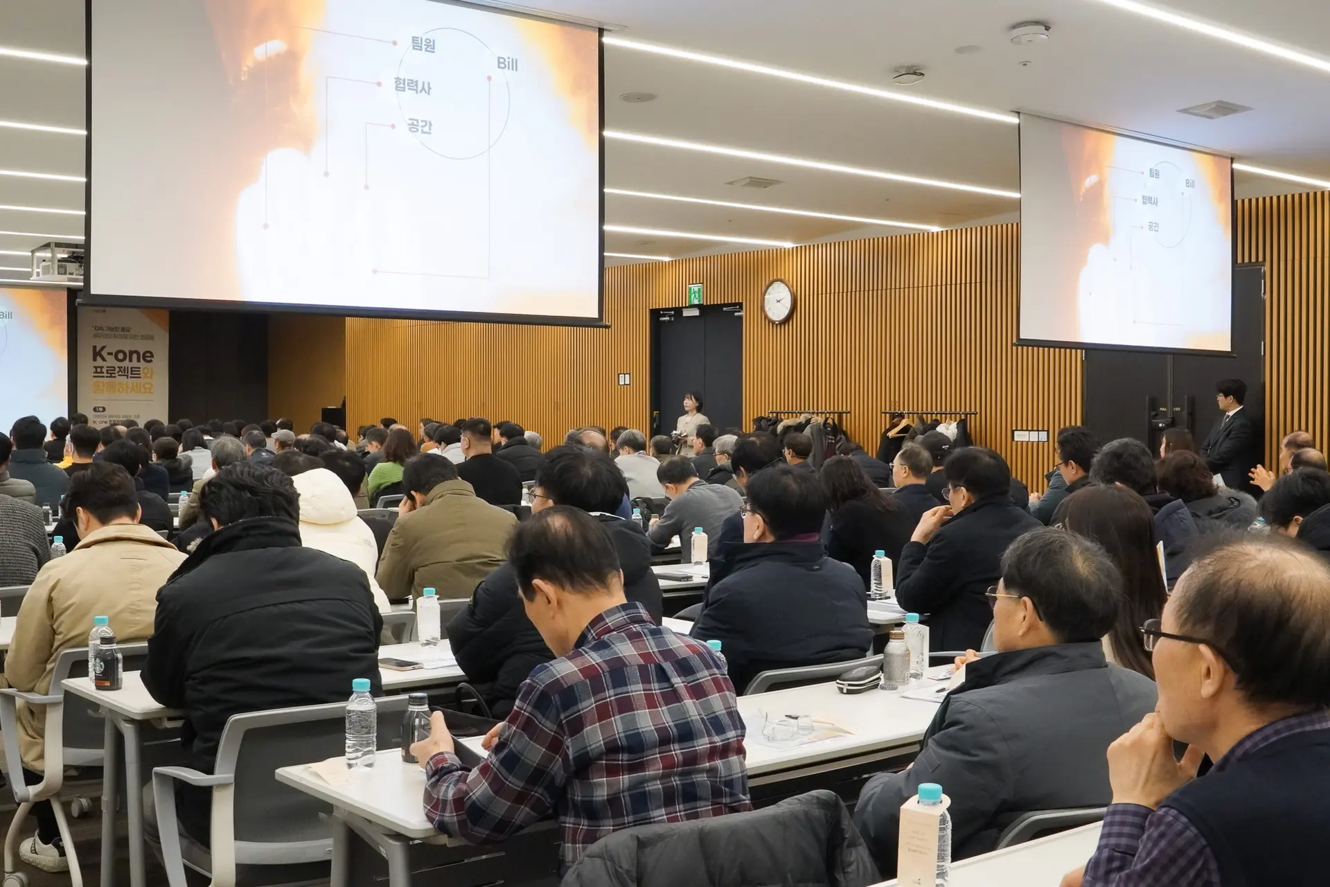 51층 대회의실 안, 설명회 진행 중 뒤편에서 촬영한 현장사진. 스크린이 뒤편 좌측, 우측에 한개씩 있고 앞쪽 가운데에 하나 있으며 스크린에는 폭발하는 사진과 구조도가 송출되고 있다.