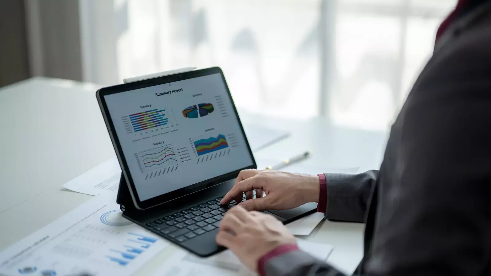 키보드 타이핑하는 사용자의 손과 태블릿 화면에 표시된 데이터 차트