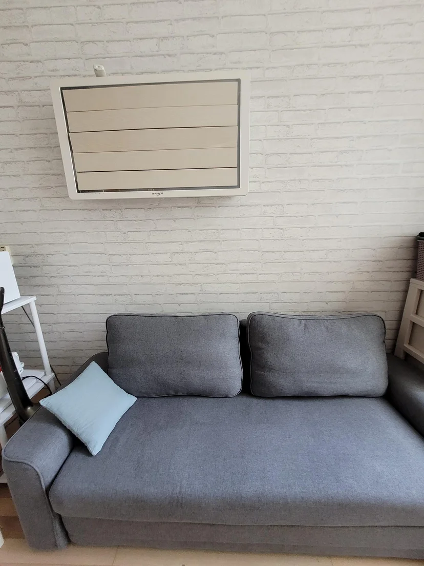 Gray sofa below a wall-mounted air conditioner (Listing ID : 3984)