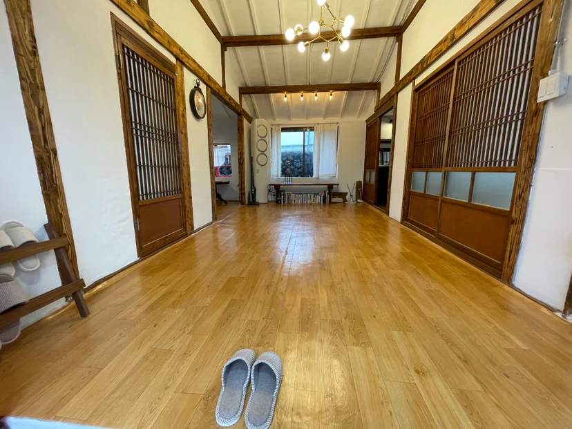 Spacious hardwood living hall with exposed wood beams, traditional latticed sliding doors, and a chandelier (Listing ID : 1954)
