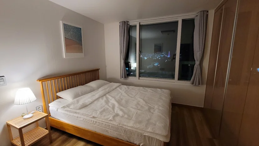 원목 침대와 야경이 보이는 창이 있는 침실