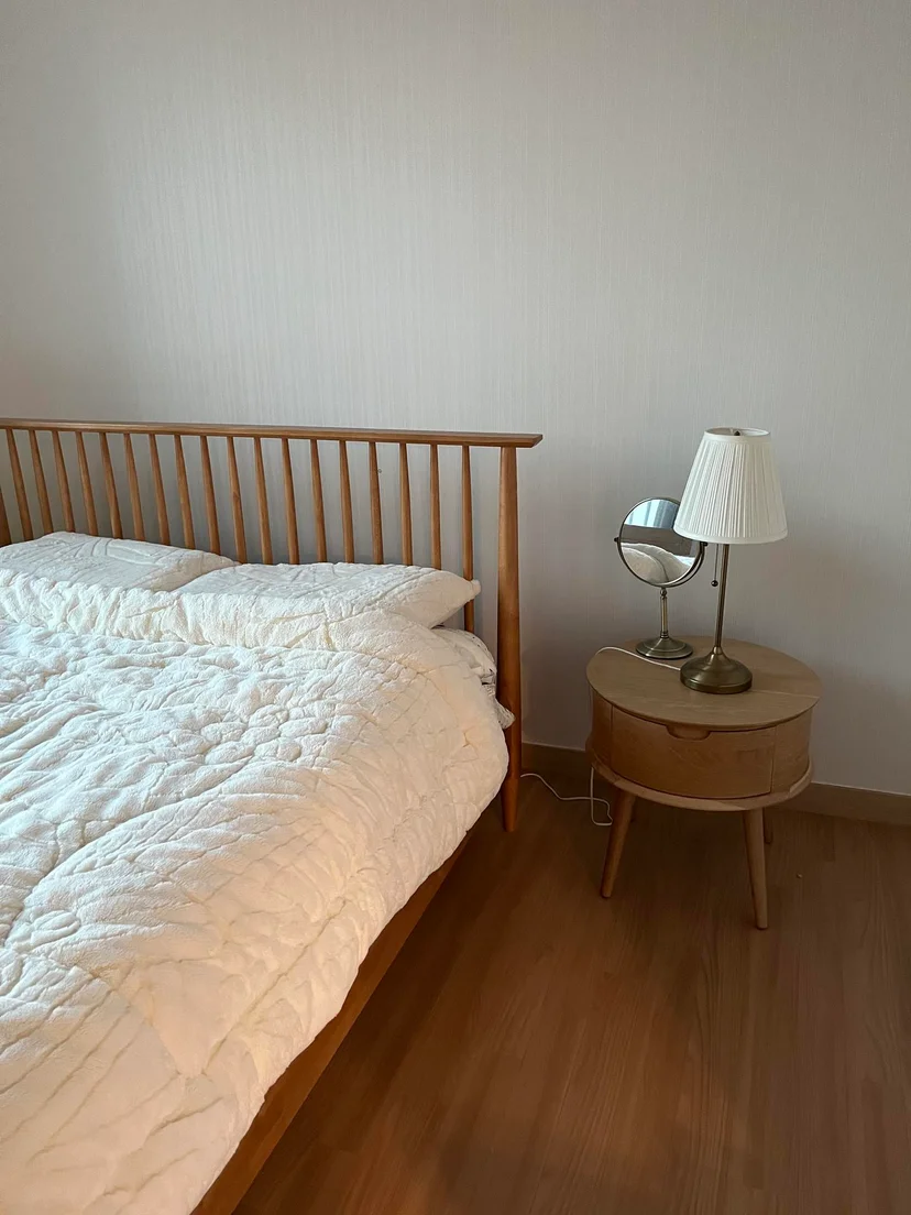 Bed with a white quilt, wooden slat headboard and a wall sconce (Listing ID : 11764)