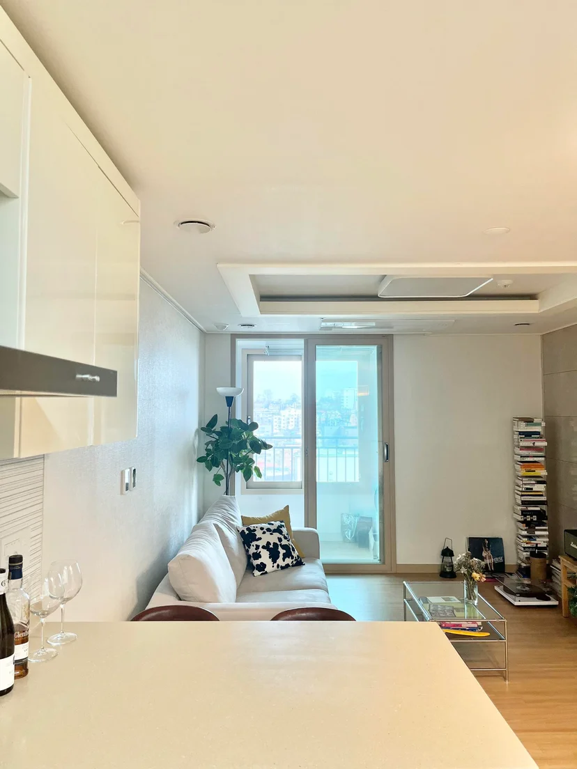 Wide view from the kitchen counter into the living room with balcony window and city outlook (Listing ID : 11764)