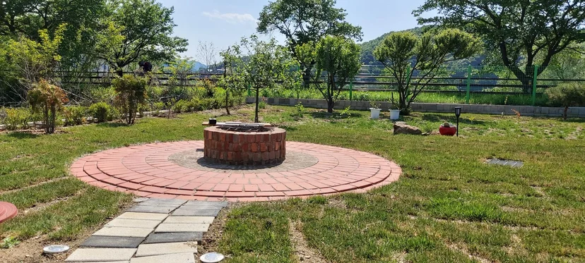 원형 적벽돌 화로대가 자리한 잔디 마당