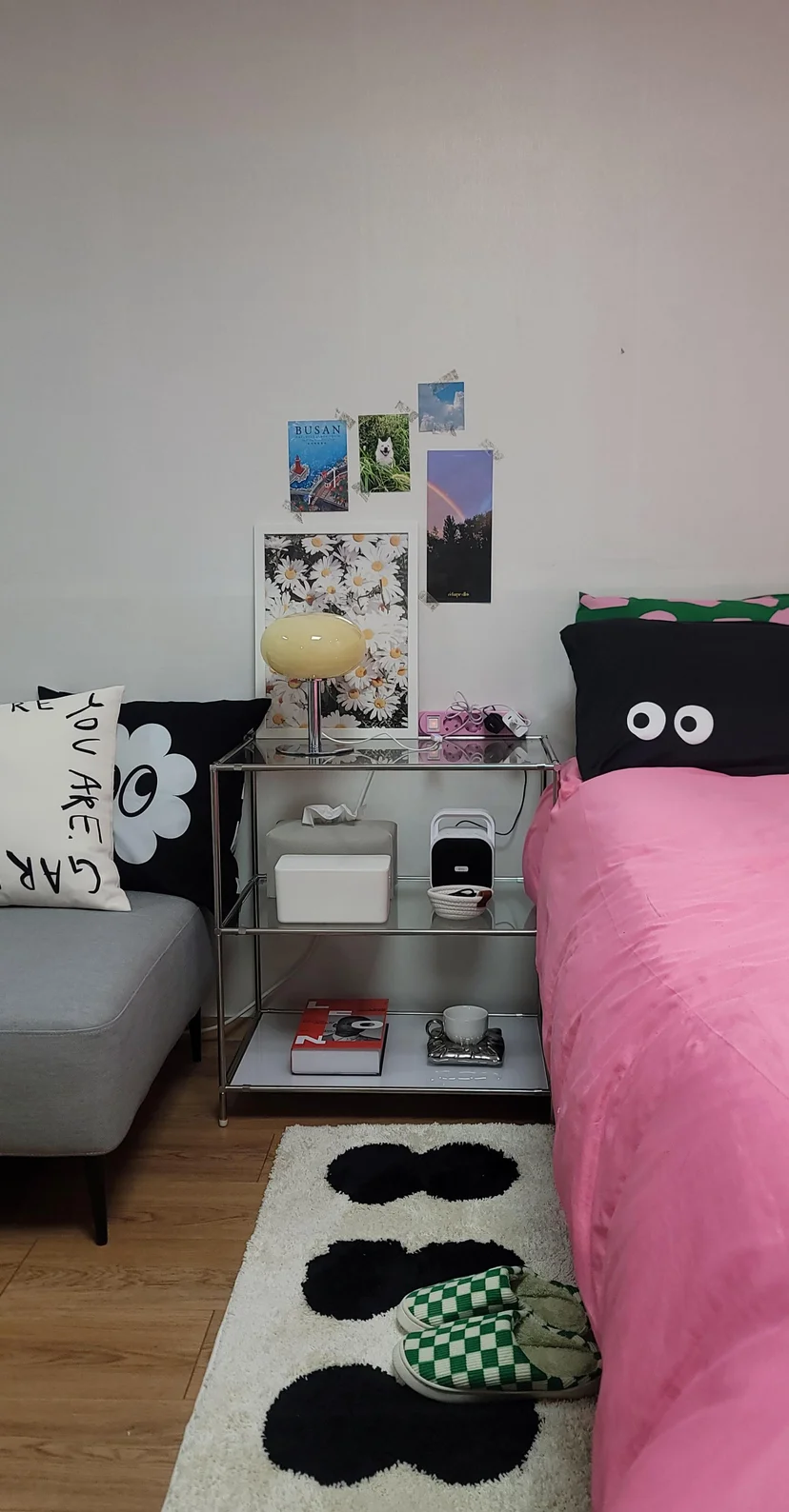 Bedroom corner with pink bed, glass side table, lamp, and decorative wall posters (Listing ID : 14800)