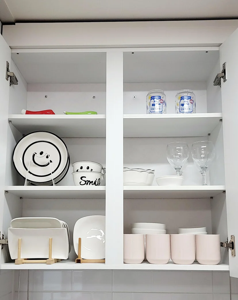 Open kitchen cabinet with plates, glasses, and mugs in the styled studio (Listing ID : 14800)