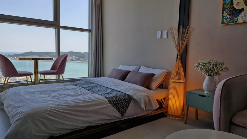 Bedroom corner with a bed, sea-view windows, a bamboo floor lamp and a mint side table (Listing ID : 22344)