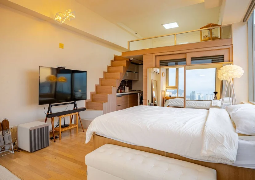 Loft studio with a double bed, wall TV, and a staircase to the upper level (Listing ID : 33770)