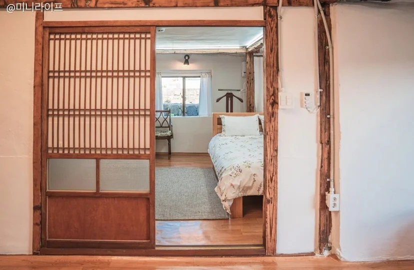 Studio living space with a low bed, built-in kitchenette, TV, sofa, and an in-unit washing machine (Listing ID : 1954)