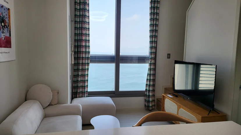 Living area with a sofa, a television and a large sea-view window (Listing ID : 21611)