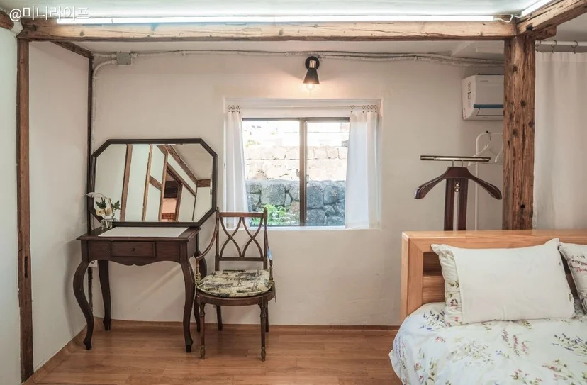 Bright bedroom with a leaf-patterned bed, framed wall art, a wooden nightstand, and yellow flowers in a vase (Listing ID : 1954)