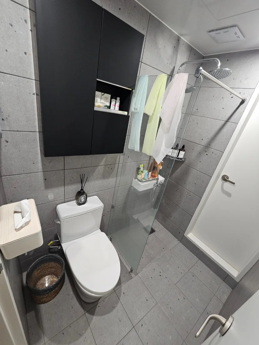 Modern gray-tiled bathroom with toilet, rainfall shower, and towels (Listing ID : 30308)