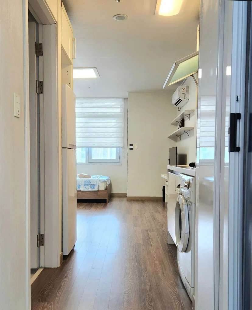 Studio interior with fridge, in-unit washer and dryer, and bed by the window (Listing ID : 31503)
