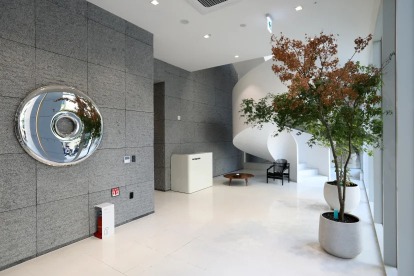 Bright building lobby with a stone wall, round mirrored sculpture and white spiral staircase (Listing ID : 45208)