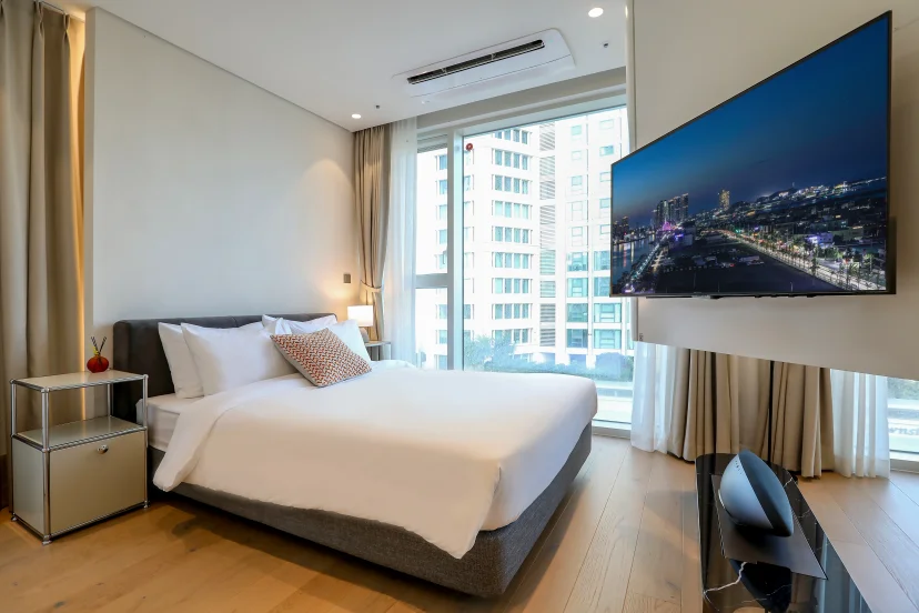 Bright bedroom with a white double bed, grey headboard and a wall-mounted TV (Listing ID : 45208)