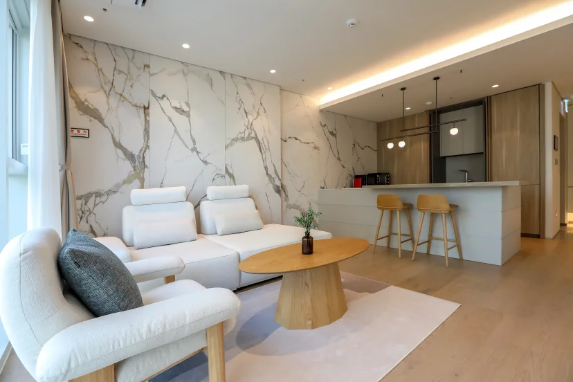 Living area with cream sofas and a kitchen island with wooden bar stools behind (Listing ID : 45208)