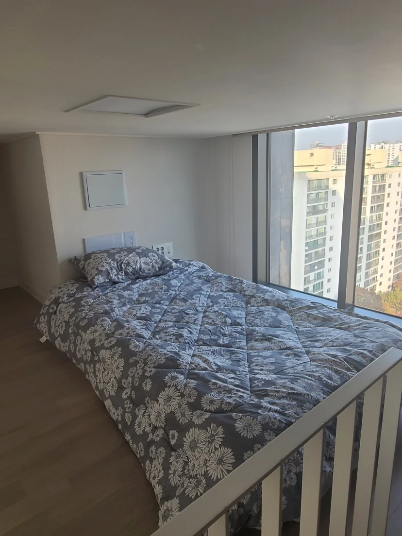 Upper-level loft bed beside a floor-to-ceiling window (Listing ID : 14692)