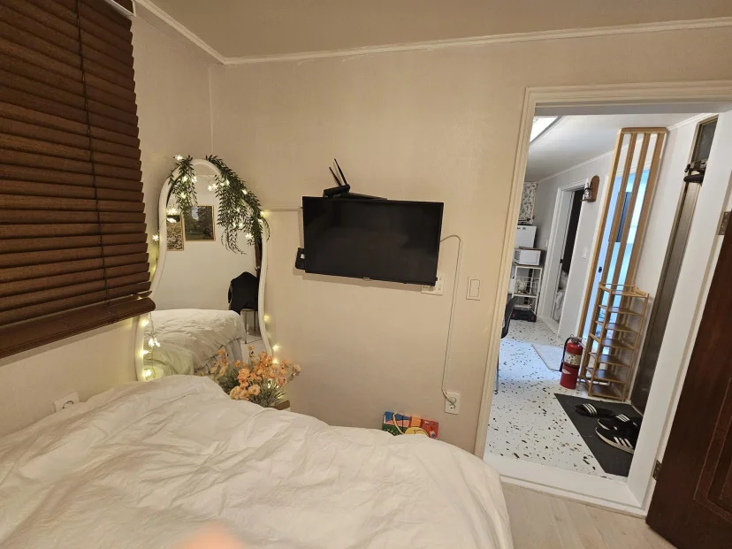 Bedroom with bed, wall-mounted TV and lit mirror beside the hallway door (Listing ID : 46711)