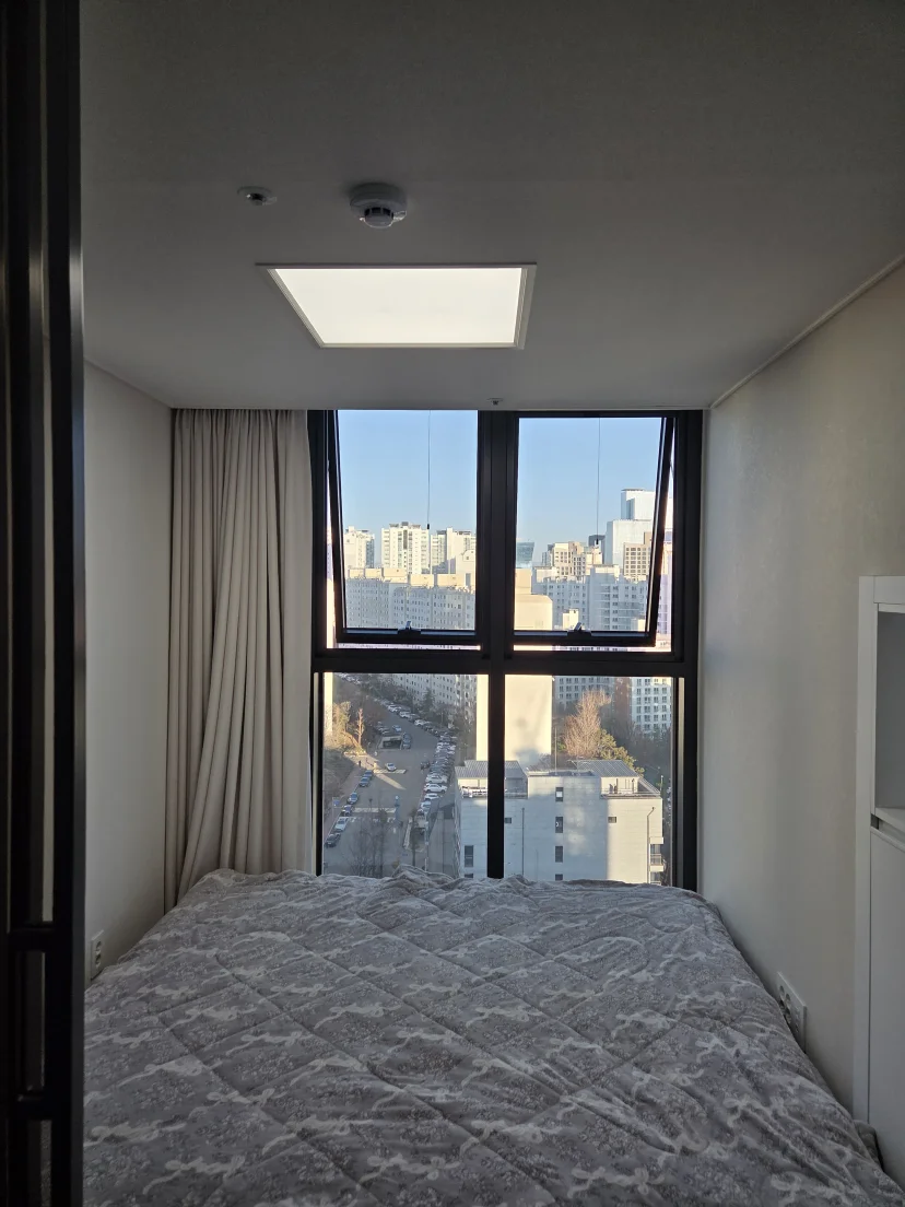 Ground-floor bed beside a full-height window over the street (Listing ID : 14692)
