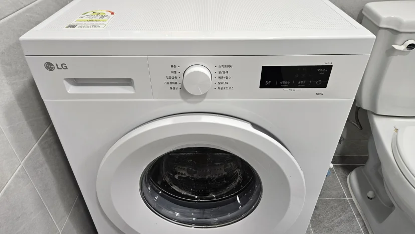 LG front-load washing machine beside toilet in tiled bathroom (Listing ID : 46906)
