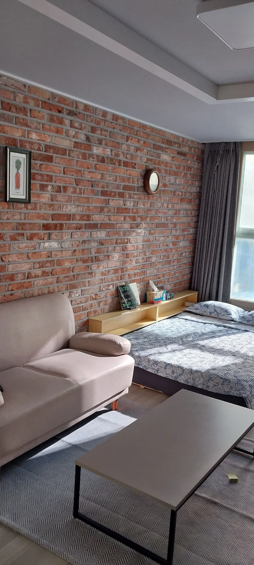 Studio living area with an exposed brick wall, sofa, and bed (Listing ID : 14737)