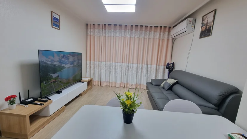 Living room with a gray leather sofa, large TV and dining table (Listing ID : 37082)