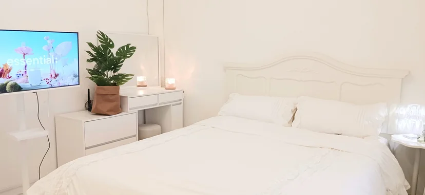 White bedroom with a double bed, dresser, and wall-mounted TV (Listing ID : 29514)