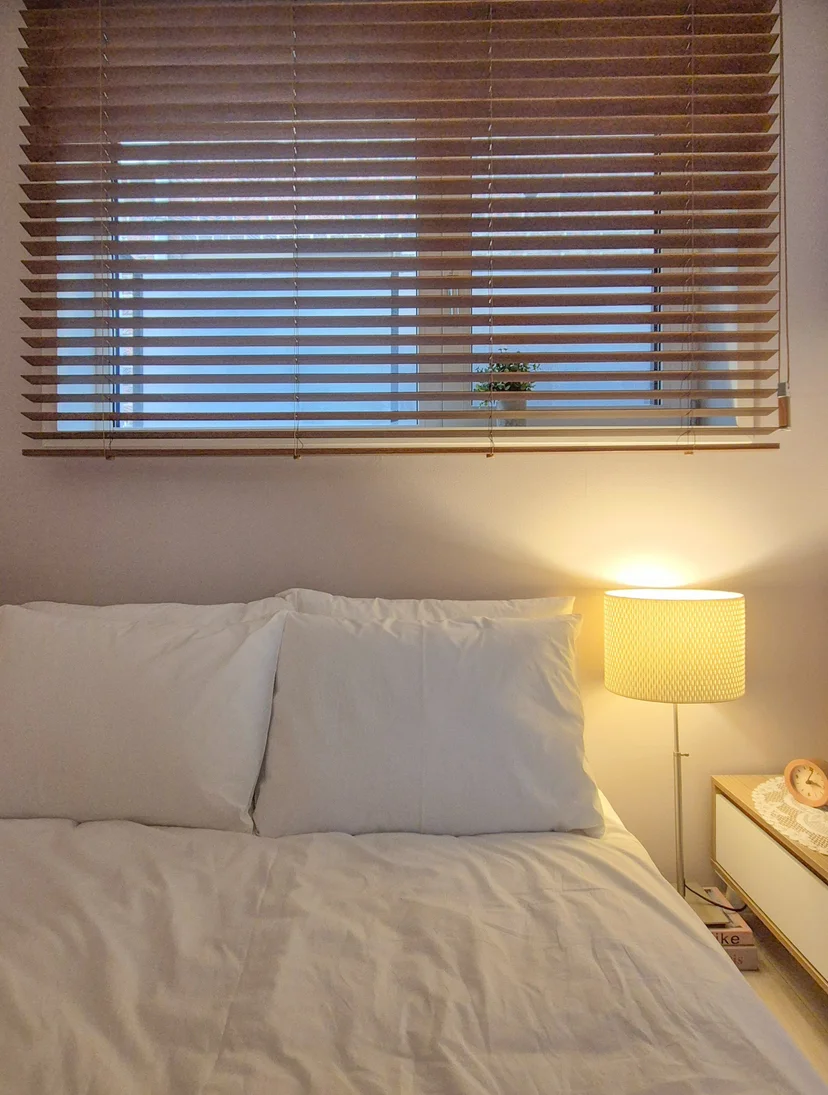Queen bed under wooden blinds with a lit floor lamp (Listing ID : 36403)