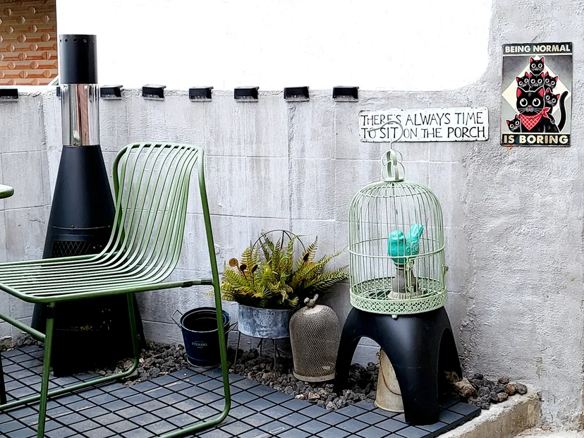 Green chair, outdoor fireplace heater and birdcage decor on a tiled deck (Listing ID : 37856)