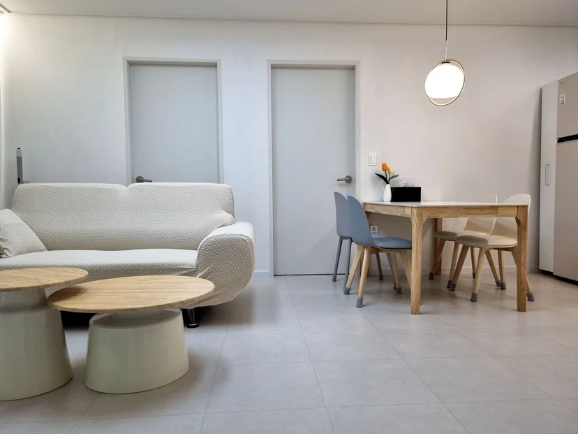 Living room with a white sofa, round nesting coffee tables, and a dining table (Listing ID : 38731)