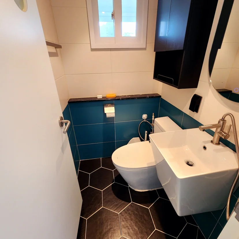 Bathroom with teal tiles, a hexagonal floor, and a wall-mounted toilet (Listing ID : 6307)