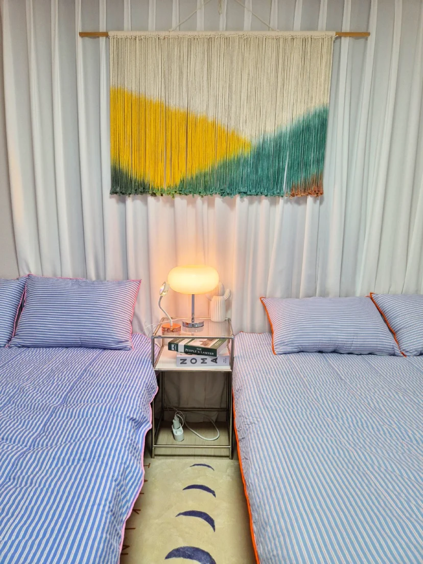 Twin beds with blue-stripe bedding and macrame wall art (Listing ID : 20556)