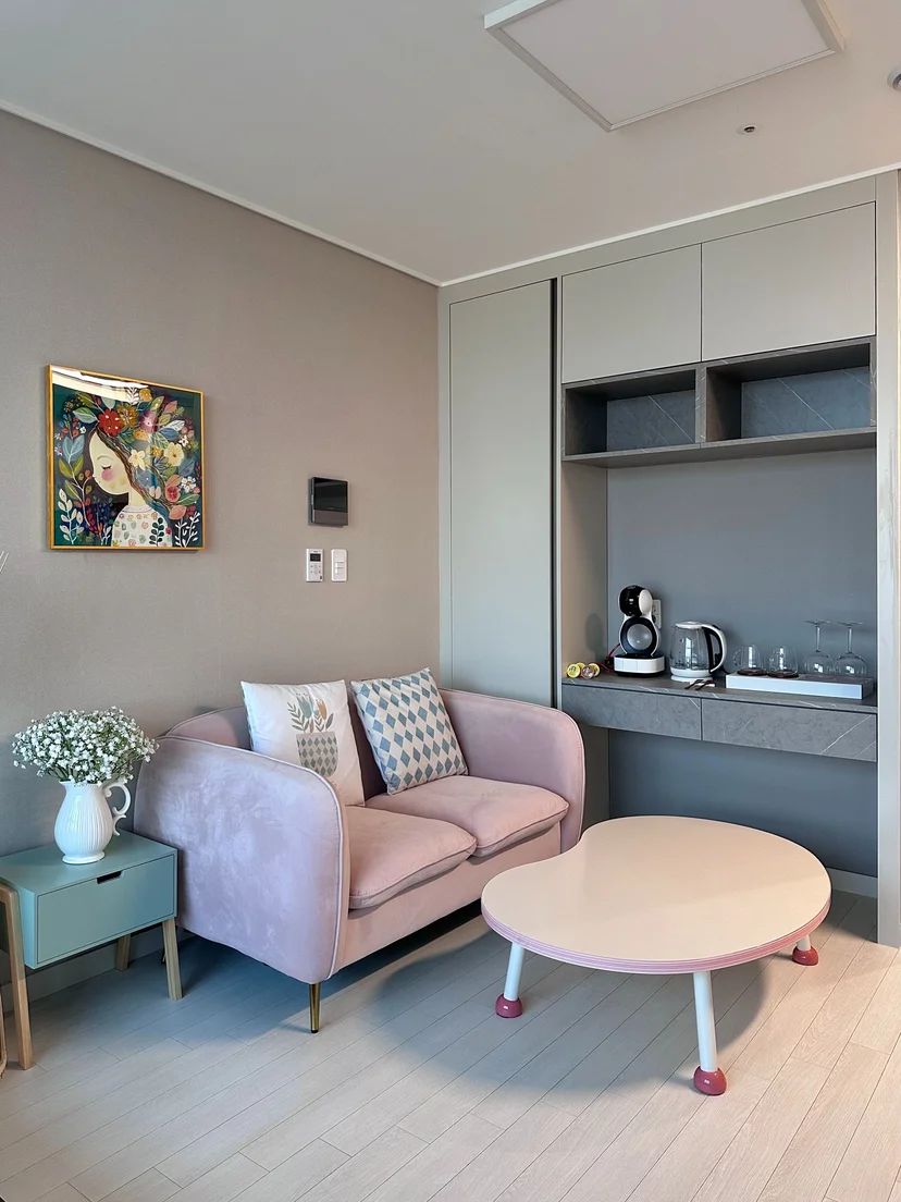 Living area with a pink sofa, coffee table, wall art and a built-in beverage counter (Listing ID : 22344)