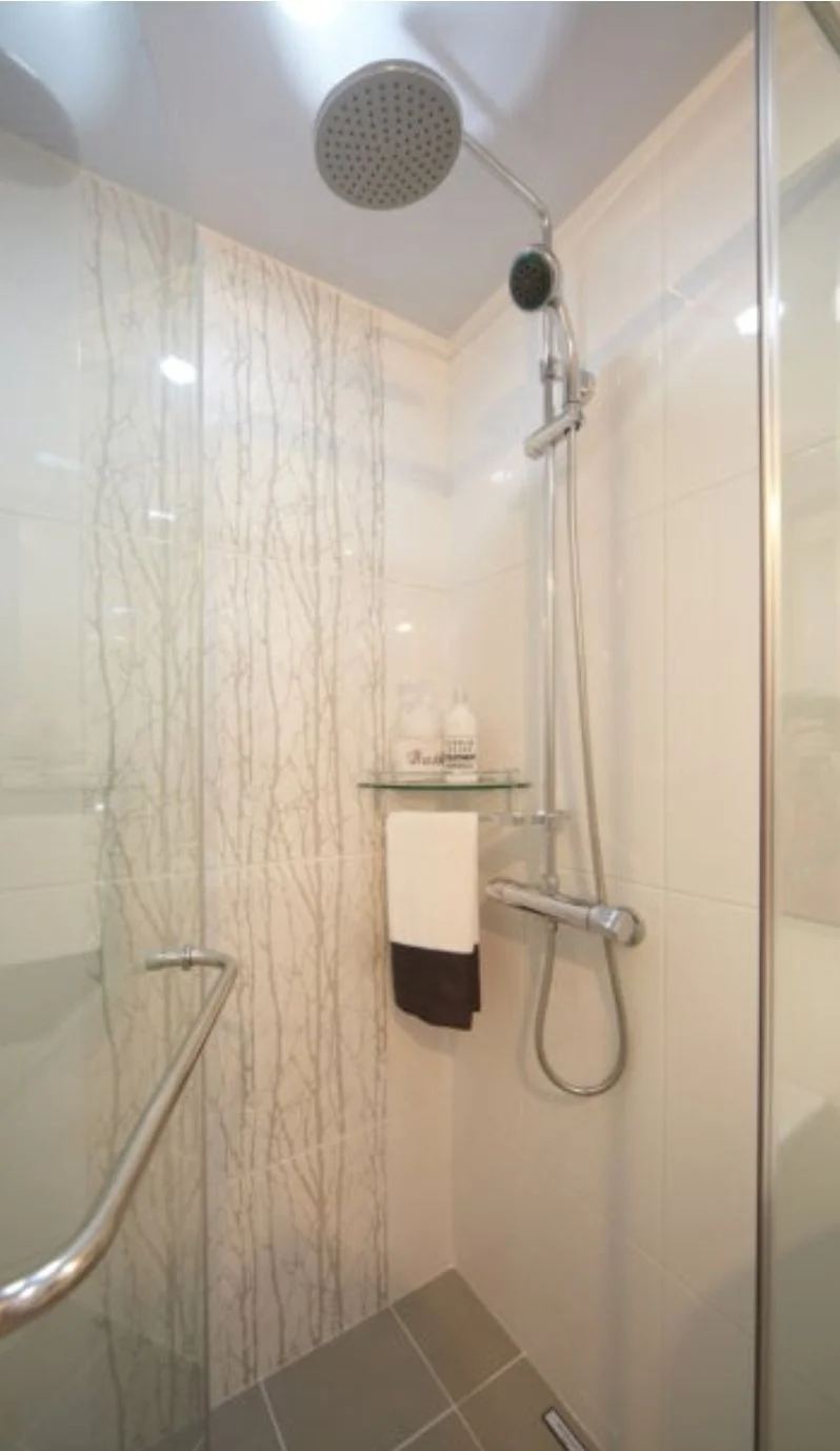 Glass shower stall with a rainfall head and toiletries on a shelf (Listing ID : 27331)