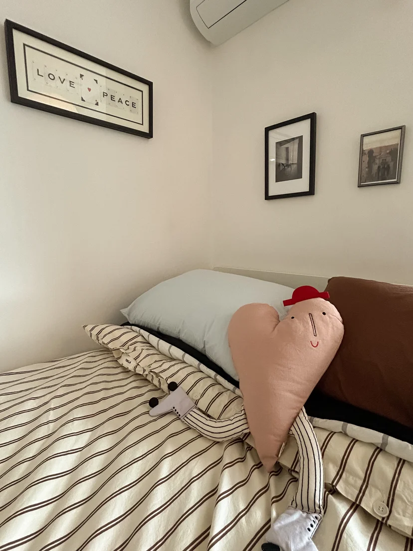 Cozy bed with striped bedding and heart-shaped cushion under framed wall art (Listing ID : 31659)