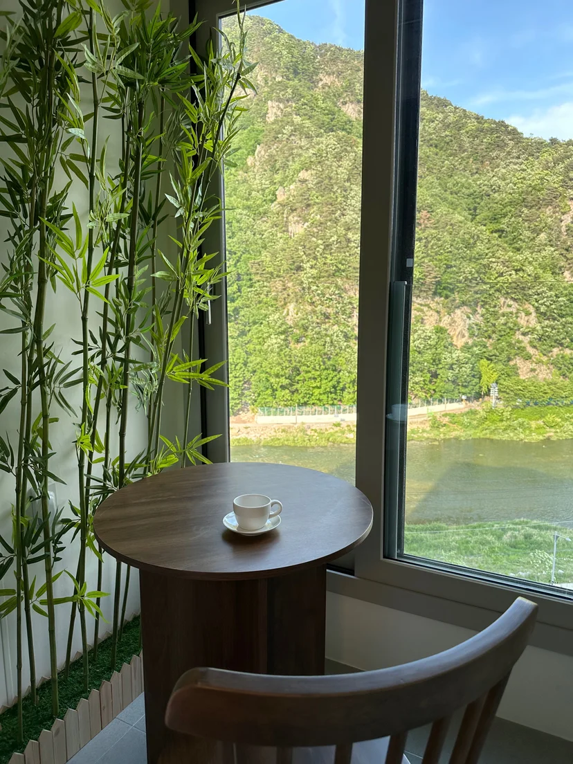 Window-side table and chair overlooking a forested mountain and the river (Listing ID : 25355)