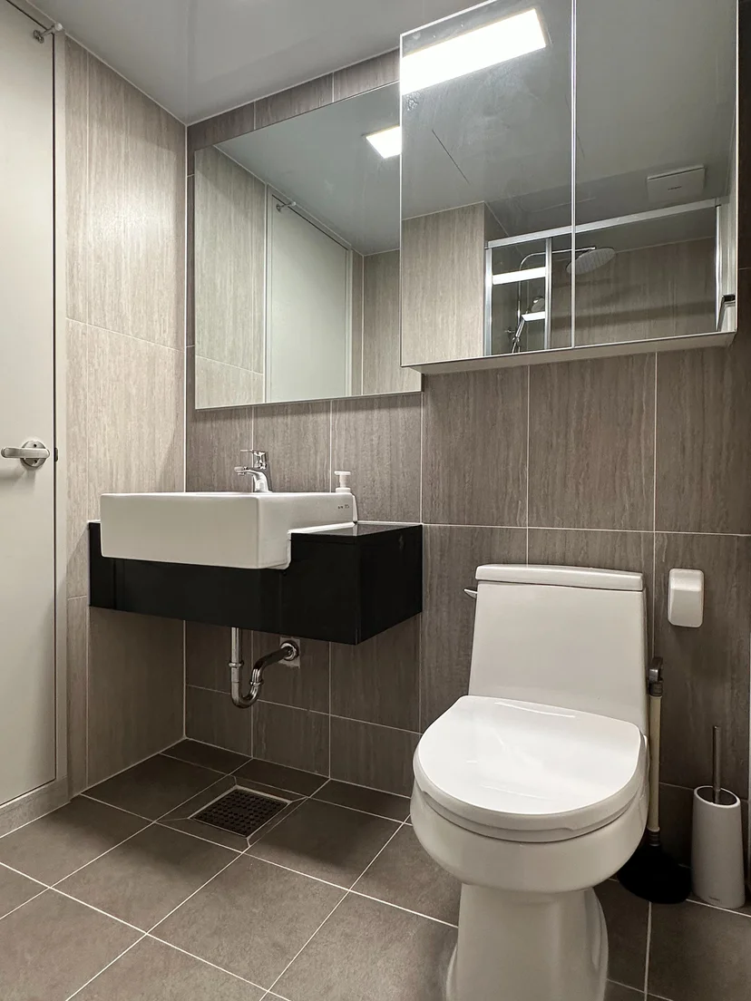 Clean bathroom with a wall-mounted sink, mirror cabinet, toilet and glass shower (Listing ID : 22344)