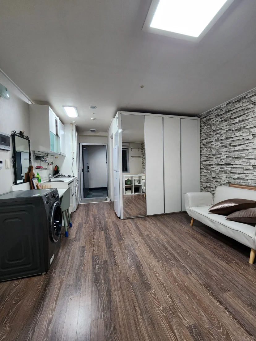 Studio with kitchenette, mirrored wardrobe, and white sofa on wood floors (Listing ID : 31503)