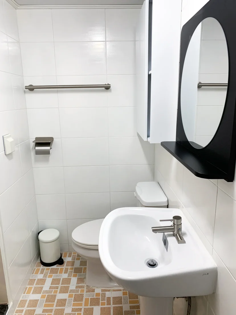 White tiled bathroom with sink, toilet and round mirror cabinet (Listing ID : 46336)