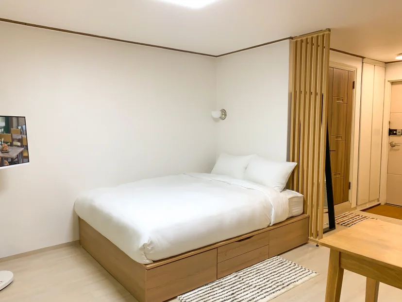 Bed with white bedding beside a wooden slat partition (Listing ID : 46336)