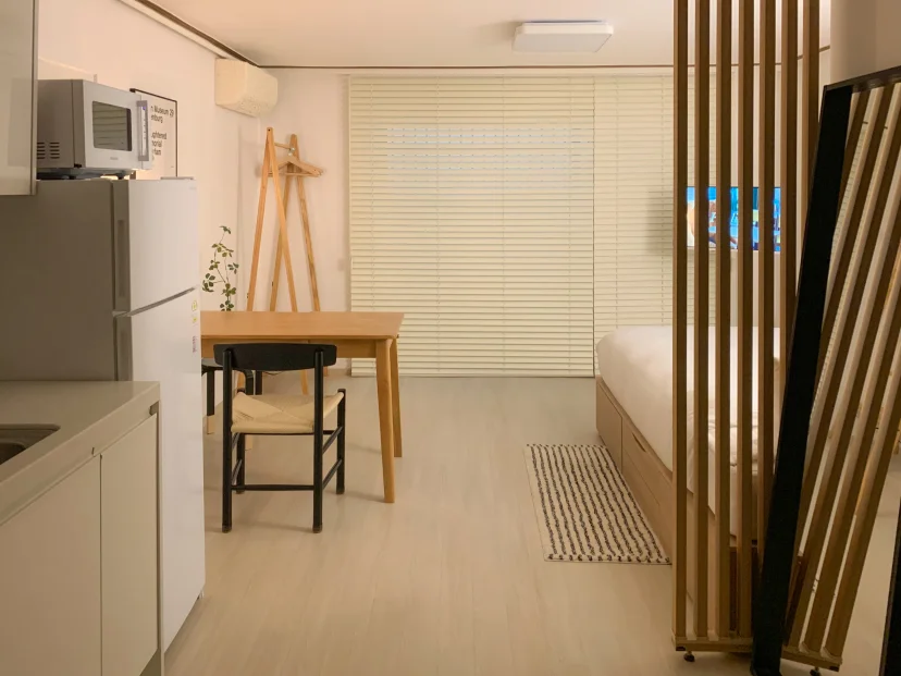 Wide view of the studio with kitchen counter, dining table and bed behind a slat partition (Listing ID : 46336)