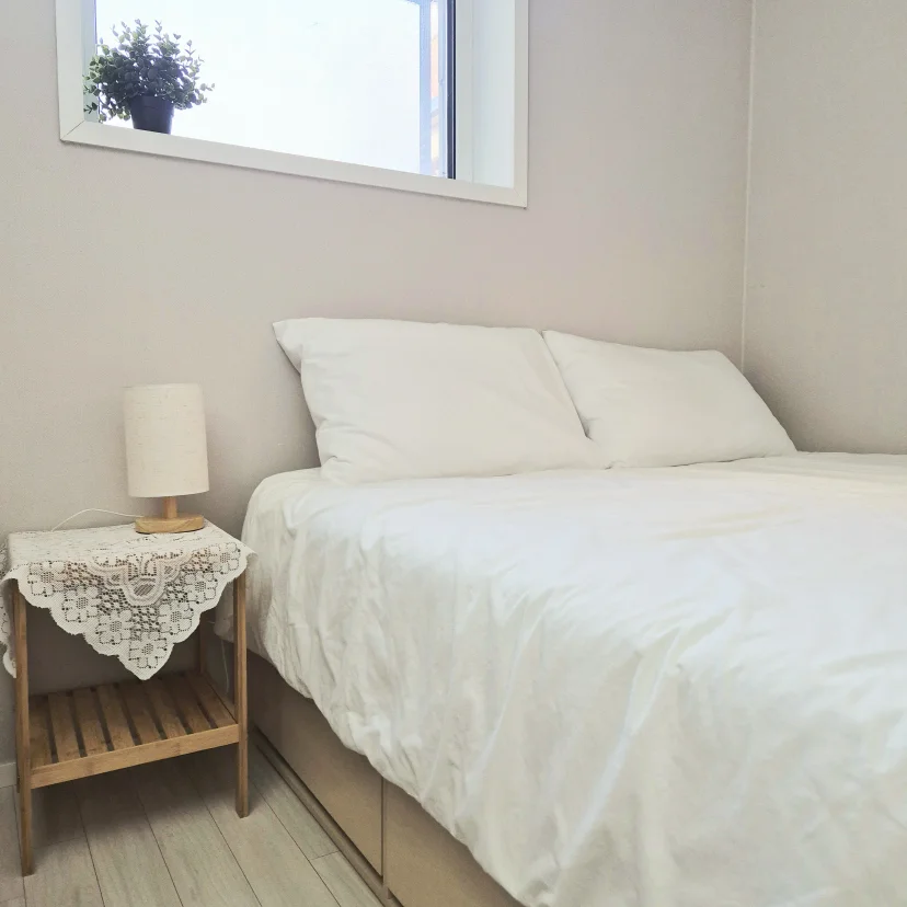 White double bed with a lace-covered bedside table and small window (Listing ID : 36403)