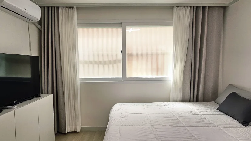 Bedroom with grey curtains, white bedding and a TV (Listing ID : 46906)