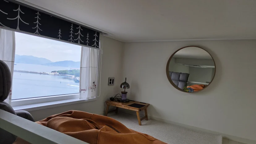 Loft sleeping area with a sea-view window and a round mirror (Listing ID : 21611)