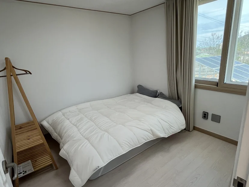 Second bedroom with a low bed frame and a window over the trees (Listing ID : 51184)