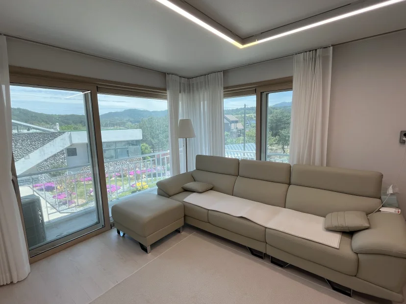 Living room with L-shaped sofa and floor-to-ceiling windows facing the hills (Listing ID : 51184)